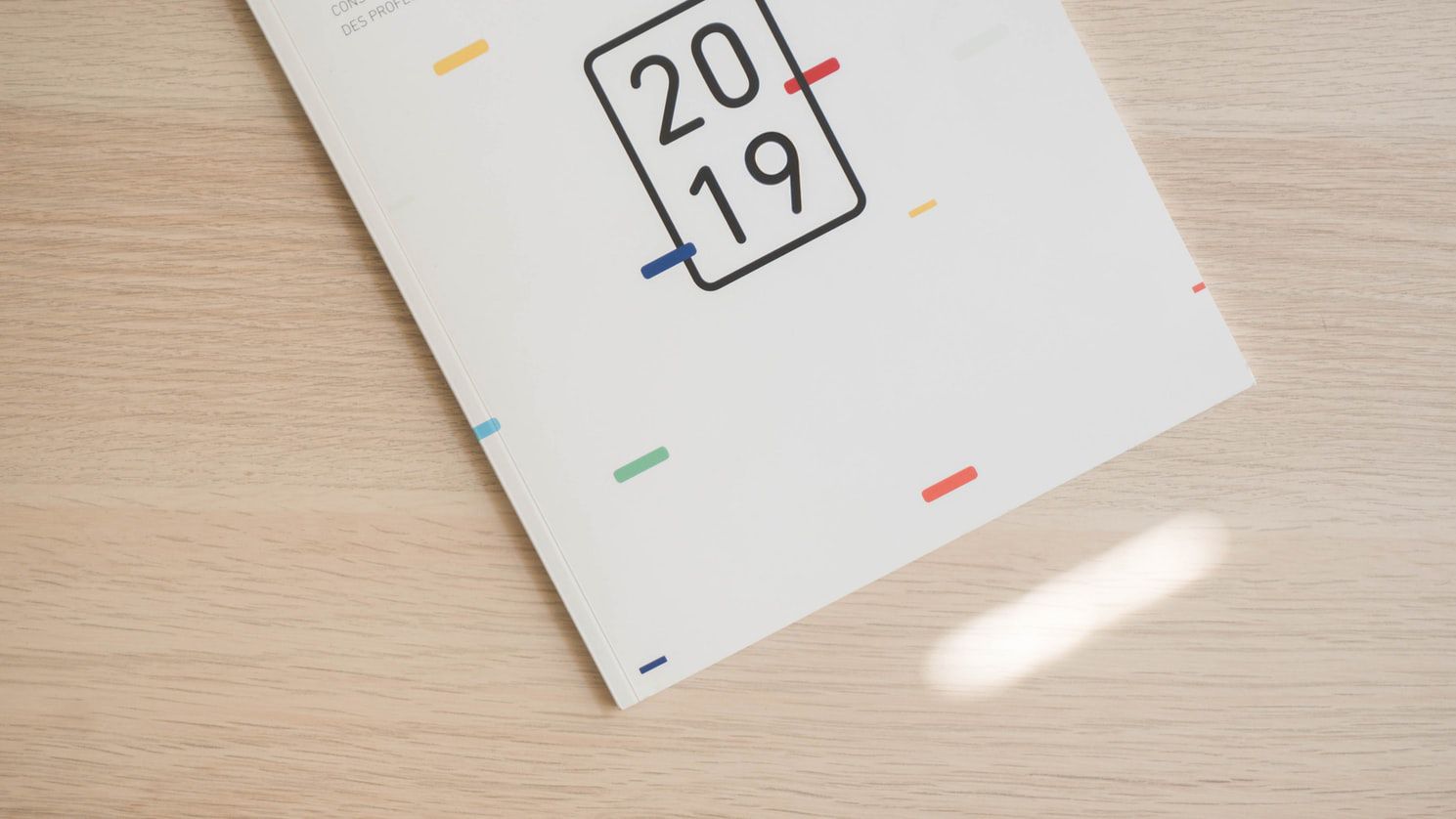 Ein 2019er Kalender liegt auf einem Holztisch und zeigt bunte Akzente um die Jahreszahl.