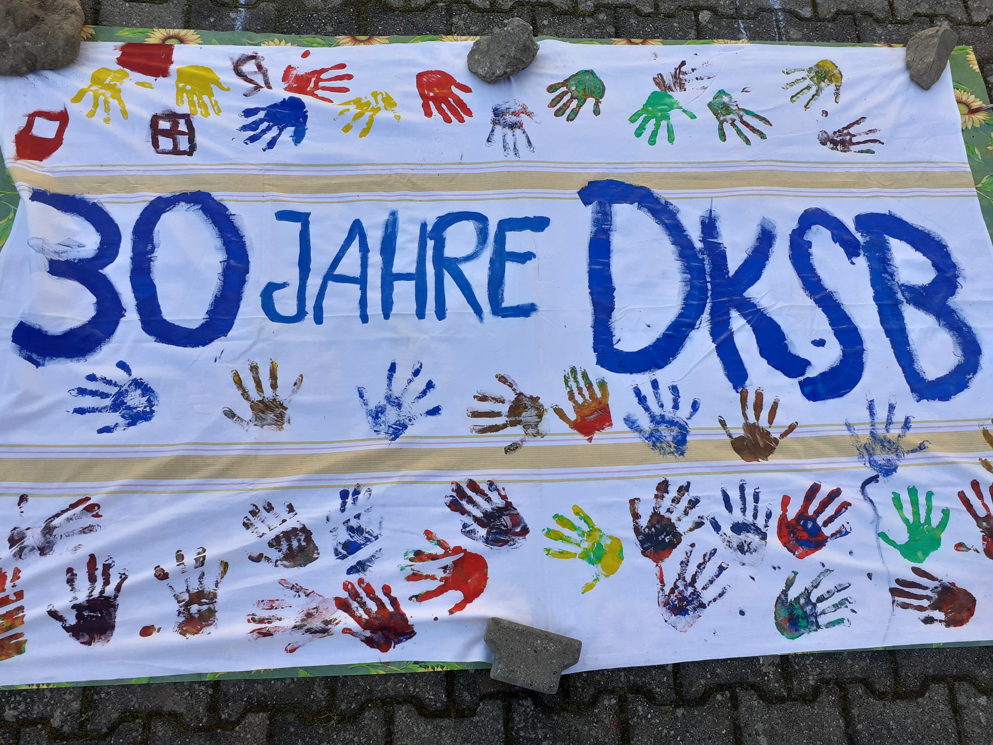 Ein bunter Banner mit Handabdrücken feiert das 30-jährige Bestehen des DKSB.